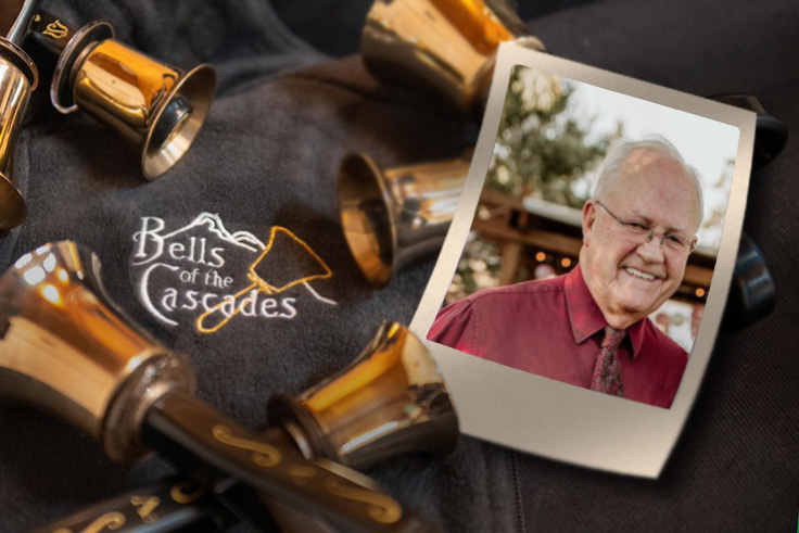 A photograph of Dick Coulter rests beside handbells on a table including an embroidered version of the Bells of the Cascades logo.