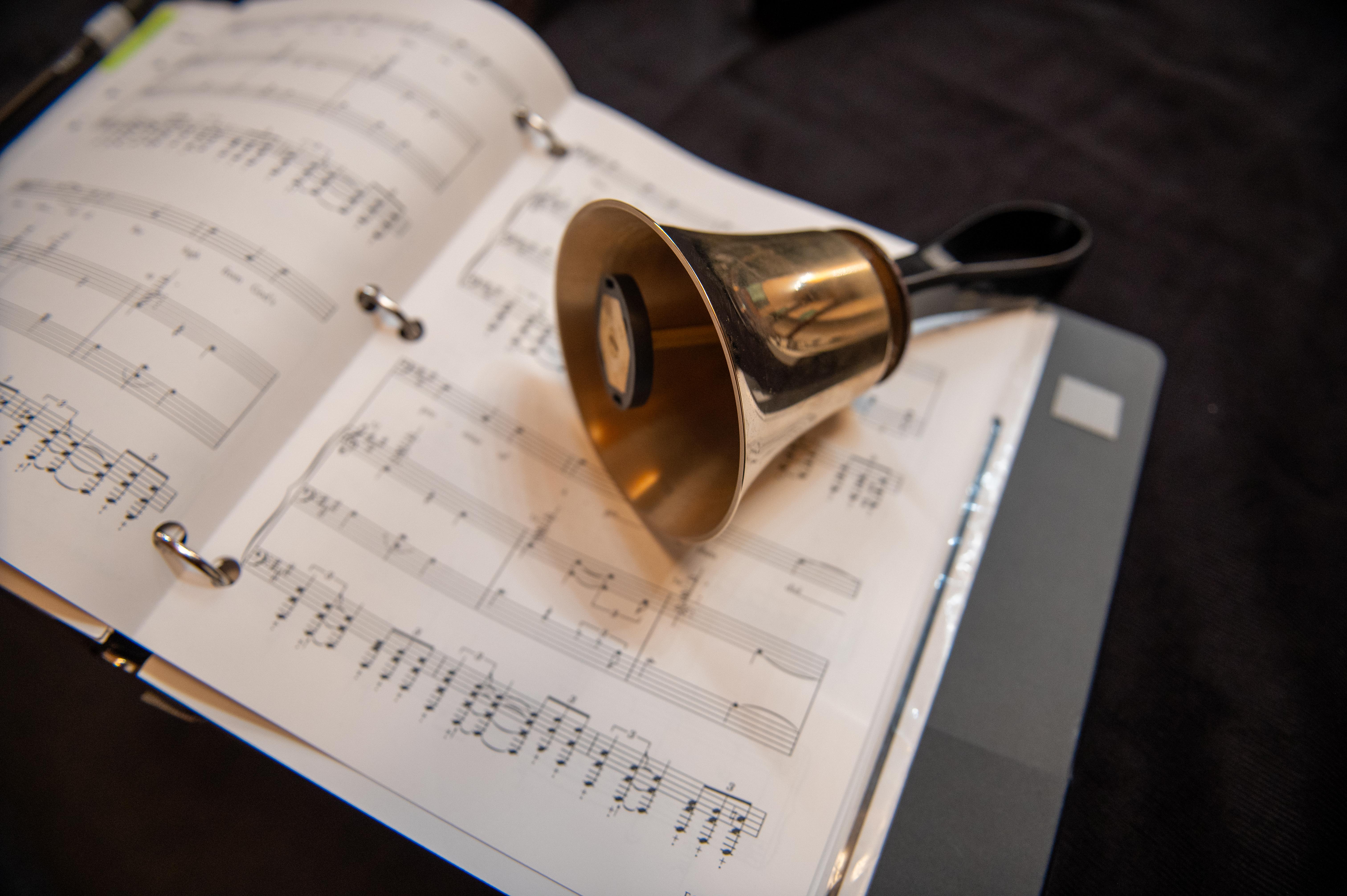 One handbell rests upon sheet music